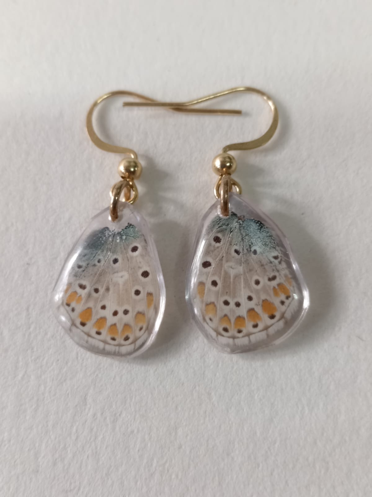 Close-up of iridescent Common Blue Butterfly wing earrings in resin